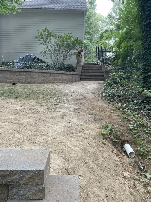 Curved retaining wall and steps terracing a graded slope behind a home