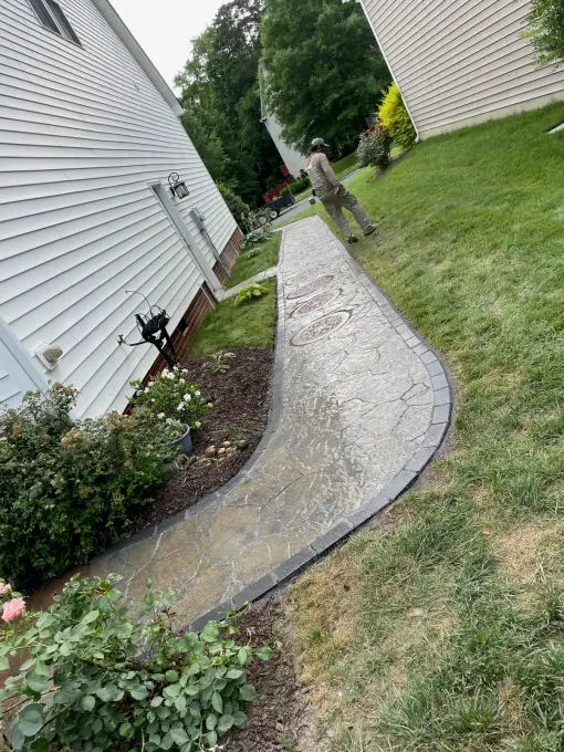 Curved flagstone walkway winding through a green lawn past blooming rose bushes
