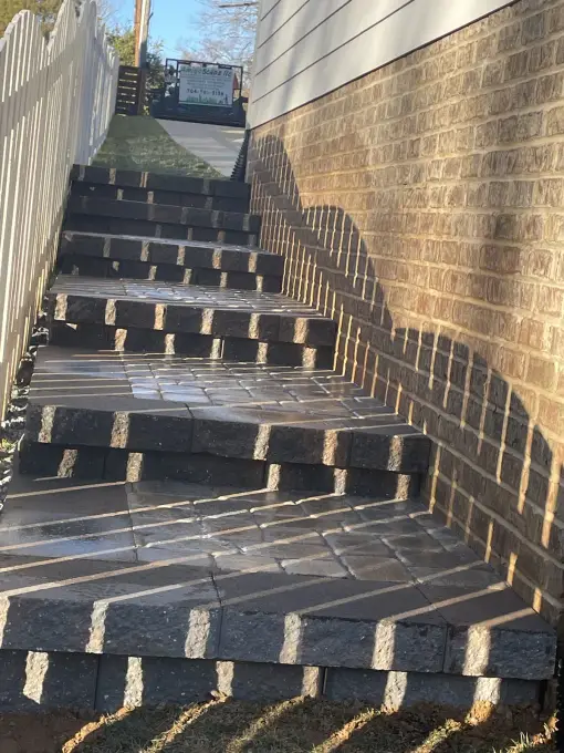 Paver staircase descending alongside a home's foundation wall