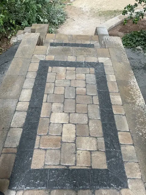 Paver walkway with a rectangular charcoal border inlay leading to a gravel garden path